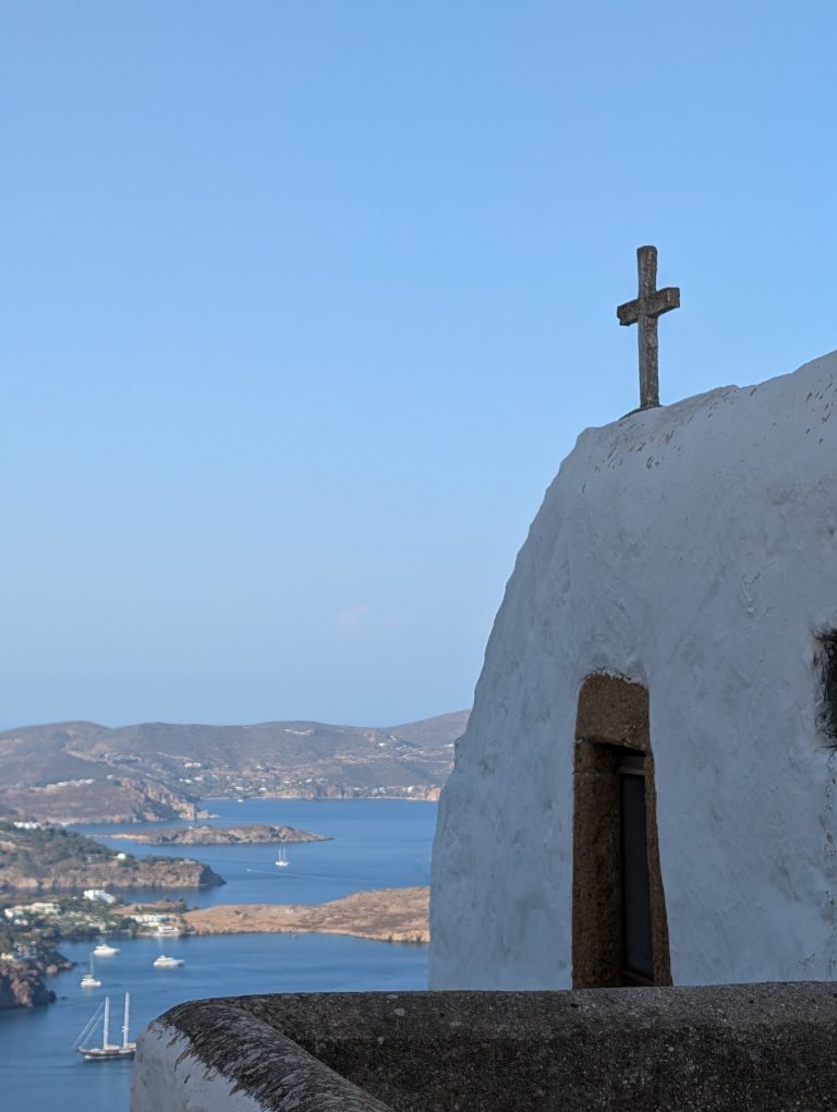 A white chapel with a cross above the sea